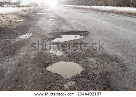 old road  potholes and holes outside city  cloudy autumn weather HDR