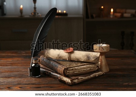 Old rolled scroll, burning candle, feather, inkwell and books on wooden table