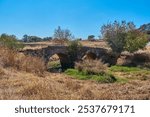 An old roman bridge on the side of a road.