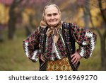 Old Romanian woman in traditional popular costume outdoor in her garden