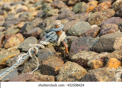 old rope tied with rusty iron on rock