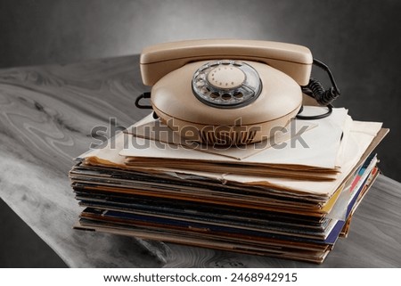 An old rotary phone on a stack of records. Vintage vinyl records old phone records from the seventies. Retro vinyl discs records and vintage telephone 