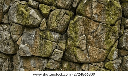Old rough stone wall texture with green moss. Ancient rock masonry background close up.