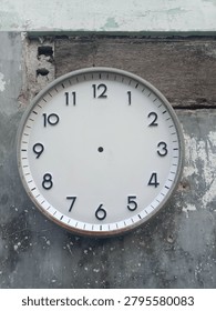Old round wall clock without hands mounted on weathered concrete and wooden wall. Rusty clock frame, urban decay texture, time concept, timeless background.