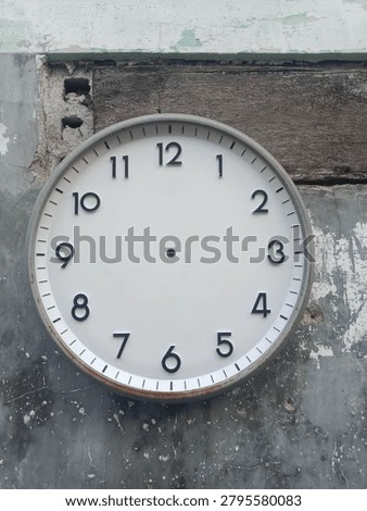 Old round wall clock without hands mounted on weathered concrete and wooden wall. Rusty clock frame, urban decay texture, time concept, timeless background.
