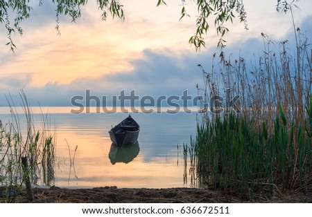 Old rowboat on the lake at sunset