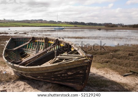 An old rowing boat in need of repair on the beach by the estuary