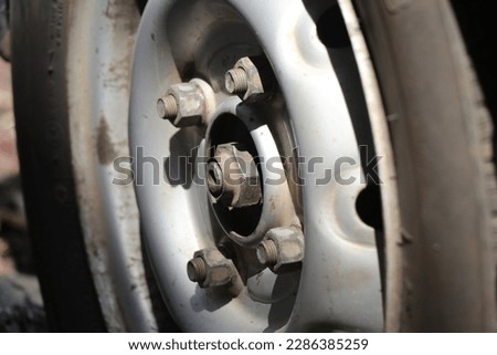 Old rubber car tyre with a view of its nut and bolt connection to shaft