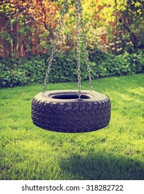 an old rubber tire swing on chains in a backyard for kids to play on toned with a retro vintage instagram filter app or action effect 