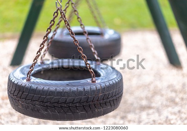 an old rubber tire swing on chains in a backyard for\
kids to play