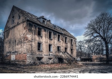 Old ruined building in a dark scenery. Left collapsing house, the object falling into ruin is probably inhabited by homeless people.