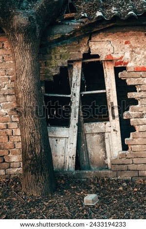 Old ruined house with damaged brick wall and broken doors ready for rundown, vertical image