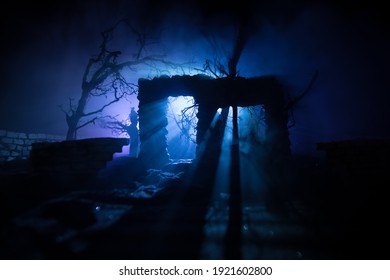 Old ruined stone house in deserted garden at night. Abandoned old mystic building with dead tree and misty backlight. Selective focus - Shutterstock ID 1921602800