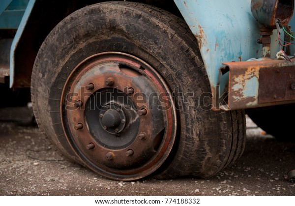 Old ruined\
truck tire, flat tire on rusted\
wheel