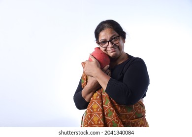 Old Rural Indian Woman Saving Money Holding A Piggy Bank And Wearing A Saree Portraying Various Expressions Of The Widow Life. She Is Confident And Portraying Savings Concept.