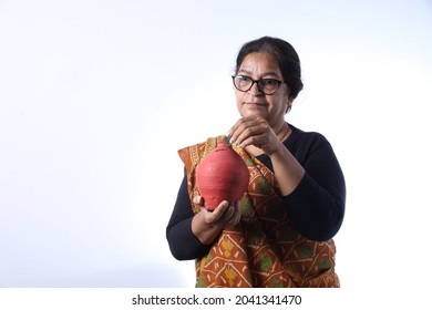 Old Rural Indian Woman Saving Money Putting A Coin Into A Piggy Bank And Wearing A Saree Portraying Various Expressions Of The Widow Life. She Is Confident And Portraying Savings Concept.