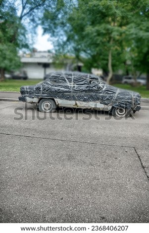 Old Russian Lada car under a car cover. A curiosity, fun strangeness. Isolated on a white background
