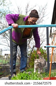 Old Russian Man Touching A Cat And Laughing