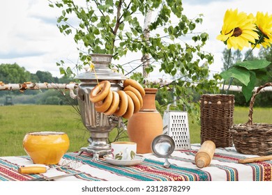 Old Russian rustic table with samovar, bagels and other kitchen utensils outdoors in the garden