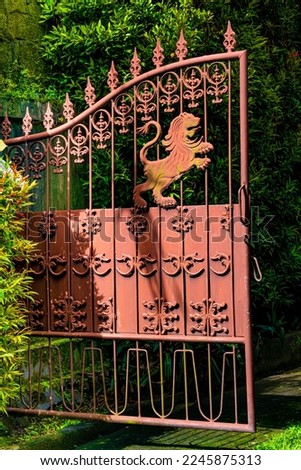 Old rust color iron gate with lion emblem for protection and scroll work in Bali Indonesia