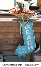 Old Rust Sign Saying 'beach This Way' Hanging In Front Of A Bar Counter. Beach Bar Decoration. Wooden Outdoor Bar At The Beach. Beach Bar Signs And Lettering.  Abstract Vacation Scene. 