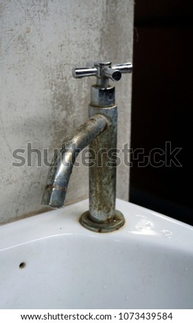 Old rust steel water tab in ceramic basin