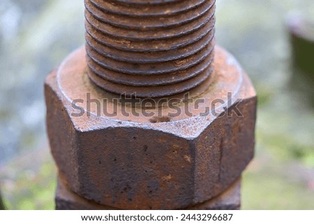 An old rusted bolt and nut hold together a metal structure.