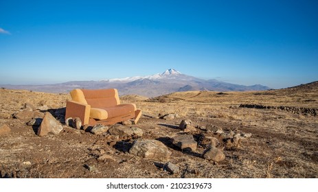 An Old Rusted Couch In The Middle Of A Big Open Field Surrounded By Mountains