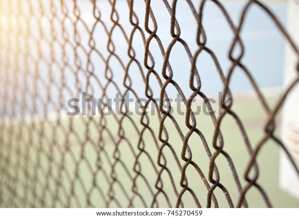 Old rusted mesh\
wire fence. Selective\
focus.