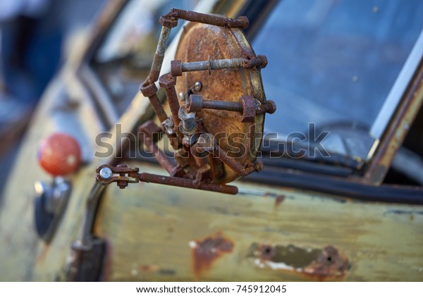 old rusted mirror creatively mounted on a vintage\
weathered German vehicle; repurposed rusty bolts make a custom and\
handmade art piece
