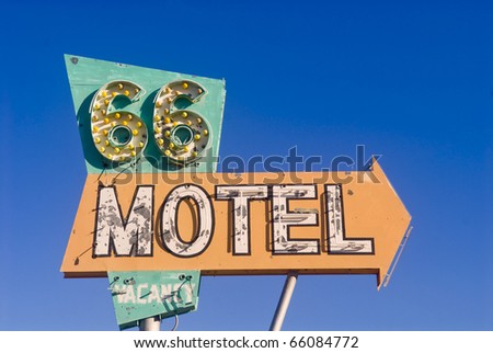 Old rusted Route 66 motel sign in front of an abandoned motel