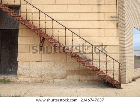 An old and rusted staircase for a fire escape door on a historic building in Honey Grove, Texas 