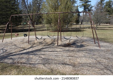 An Old Rusted Swing Set In A Park