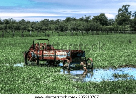 An old rusted tractor wagon near the pond in the field
