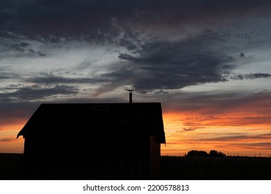 An old rustic farm building silhouette on the Alberta prairies at sunrise in Rocky View County Canada