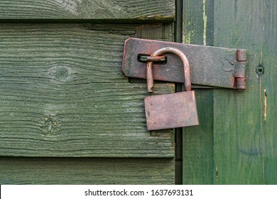 Old rustic metal open padlock against a worn green wooden door. - Powered by Shutterstock