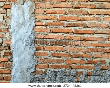 Old rustic red brick wall texture with rough gray cement plaster patches. Ideal for construction backgrounds, urban architecture, and industrial design themes