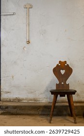 an old rustic wooden chair against a grungy and dirty white wall in an abandoned building