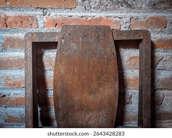Old rustic wooden chair against a red brick wall, showing aged wood texture and vintage style furniture in a traditional interior