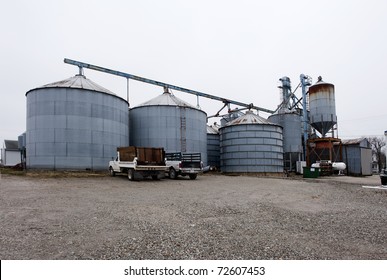 Old, Rusting Grain Silos On A Gravel Parking Lot