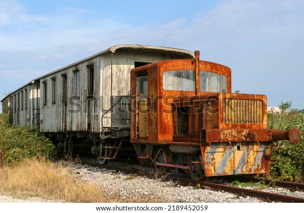 Old rusty and abandoned\
train, on track, consisting of diesel locomotive and old wooden\
wagons.