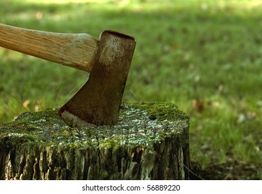 old rusty axe embedded in a tree stump