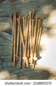 A lot of old rusty bent nails lying on a wooden board.