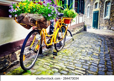 Old rusty bicycle with flowers leaning against house wall