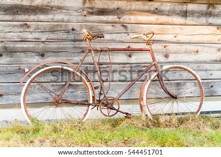 Old and rusty bike abandoned outside a wooden cabin a long time ago.