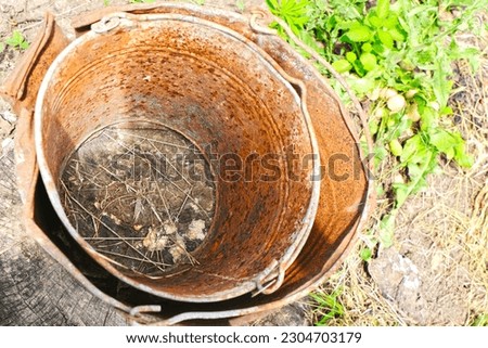 Old rusty broken bucket without a bottom. Ancient Ukrainian Slavic dishes. Historical folk art, pottery. Summer suburb greenery view. Countryside. Farming, gardening. Hobby. Harvest. Small business.