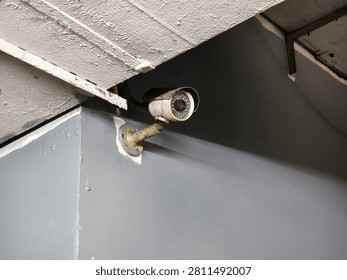 Old rusty bullet CCTV security camera mounted on concrete wall corner