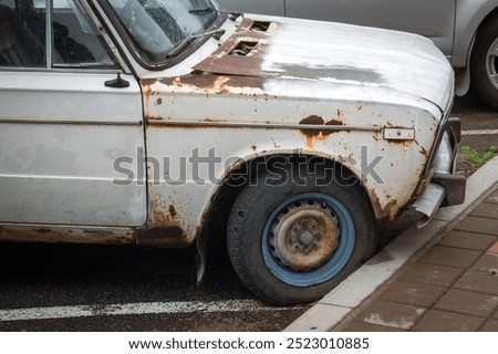 Old rusty car close up. Vehicle recycling concept. Bonnet and wing of white car in parking lot. Recycling price