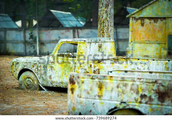 An old rusty car in\
paint from paintball