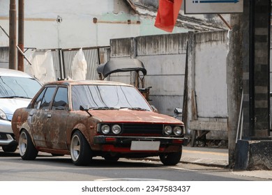 Old rusty car parked on roadside. Vintage car parking on street side. Front view - Powered by Shutterstock